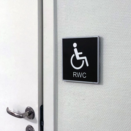 Signcode 148x148 med signcode hållare utanför handikapptoalett på Kungsörs gymnasium